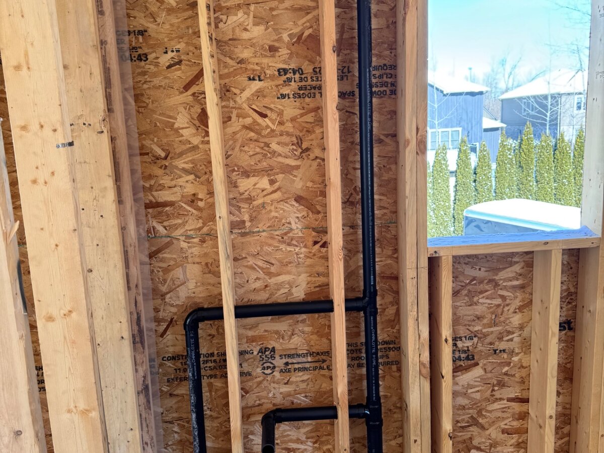 New construction plumbing rough-in with ABS drain and vent piping and PEX water lines in a framed stud wall