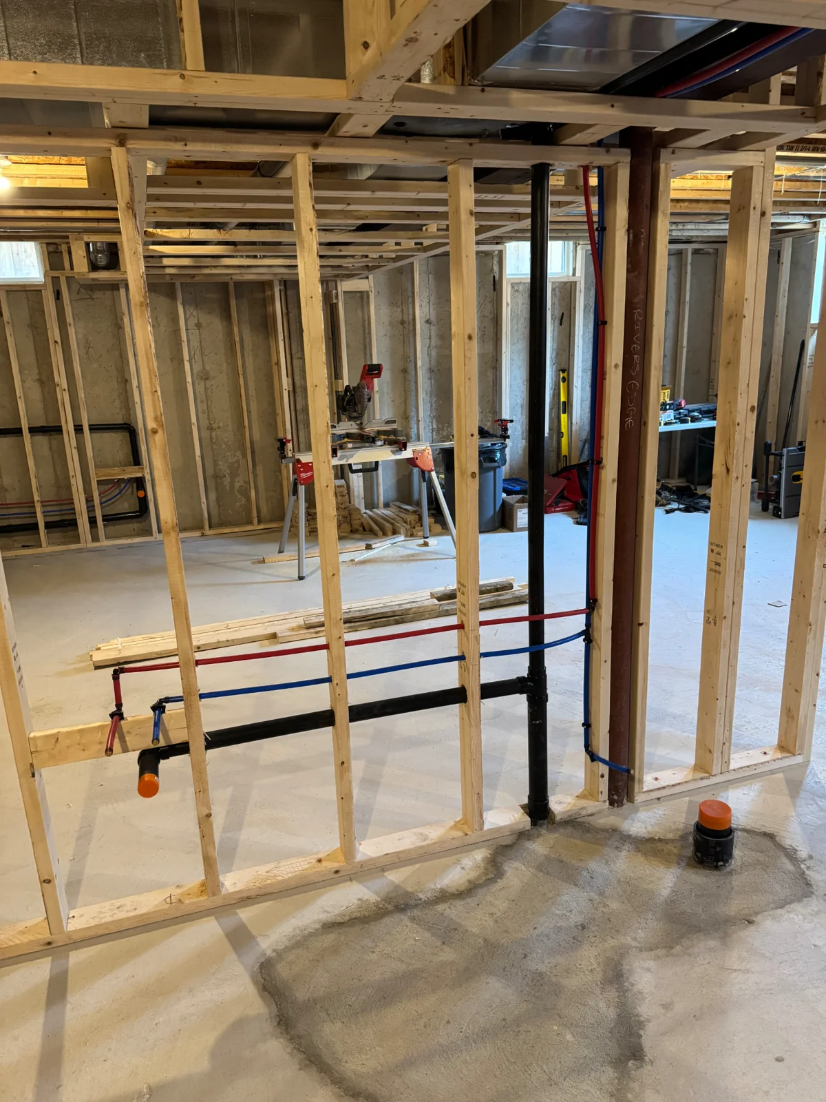ABS drain stack and red and blue water lines in framed basement walls
